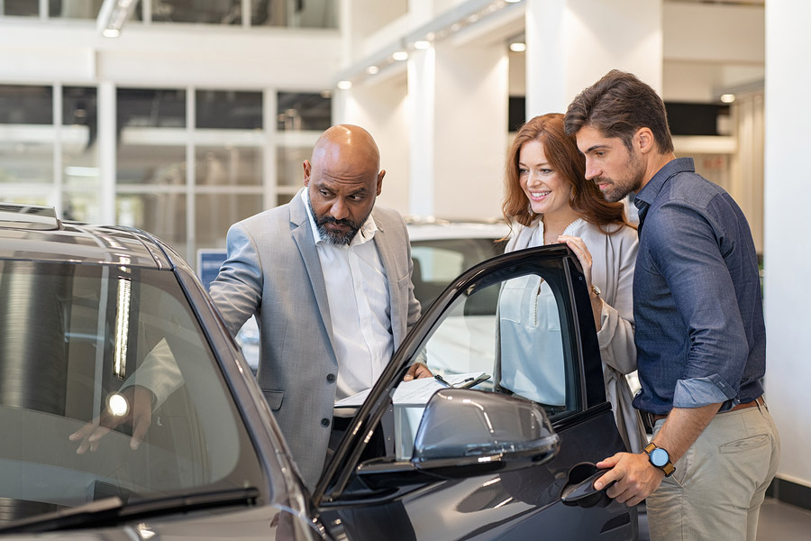 Sales person demonstrating a car with some clients